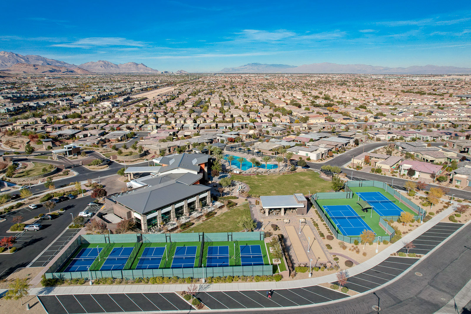 Aerial view of the Regency clubhouse, pool, and pickleball courts with the Las Vegas Valley and mountains in the background