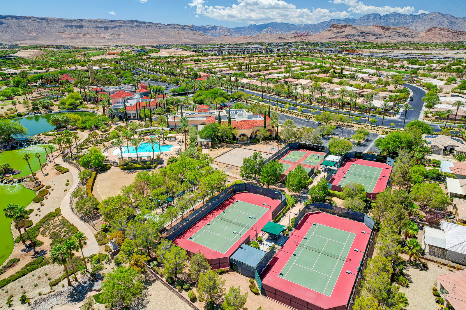Aerial view of Siena's tennis and pickleball courts, pool, and clock tower with mountain views