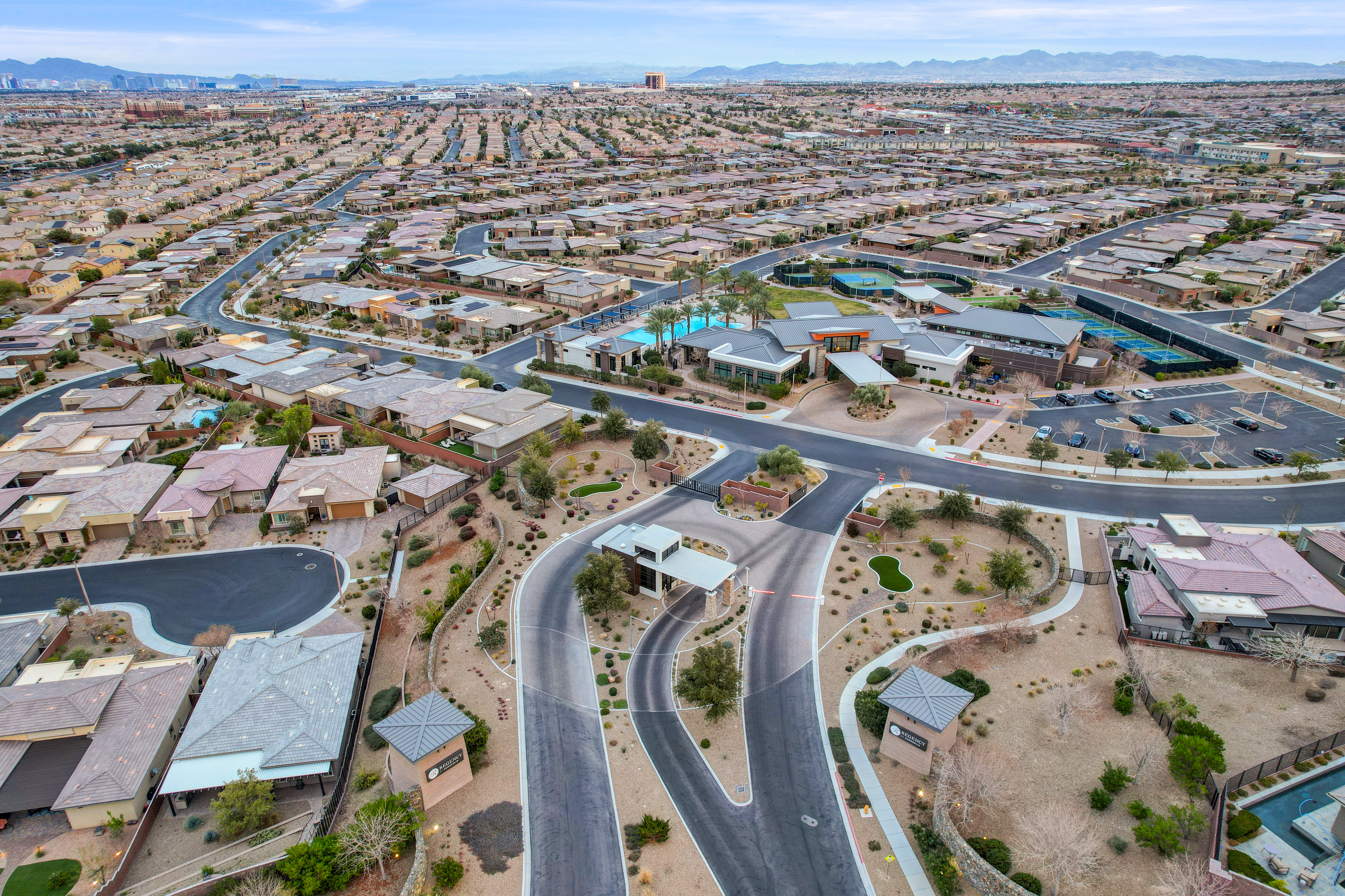 Aerial view of Regency at Summerlin's guard-gated entrance, clubhouse, pool, and tennis courts surrounded by the community's single-story homes in Las Vegas, Nevada