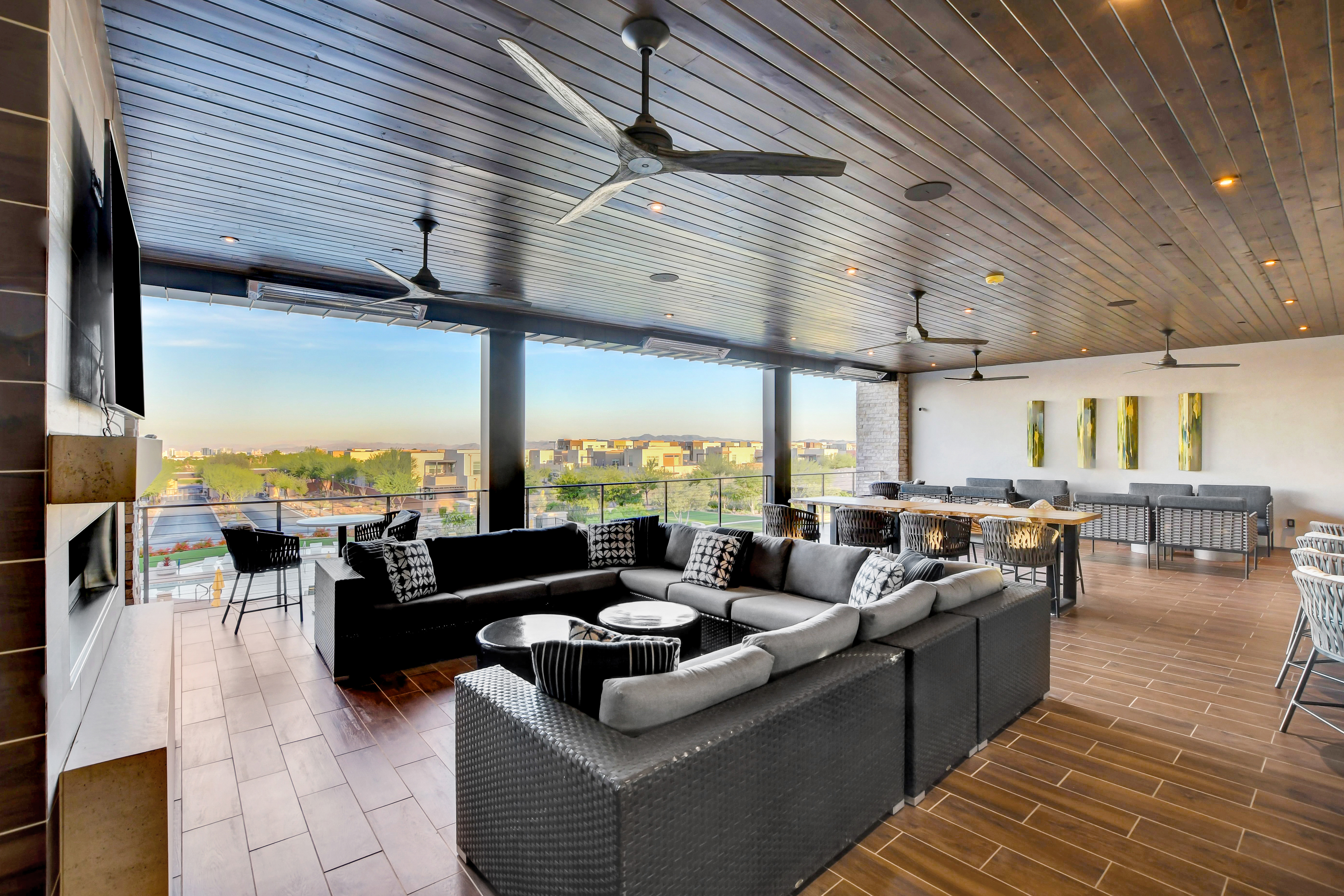 Upstairs sports and media lounge at the Outlook Club with sectional seating, a fireplace, and a view over the community