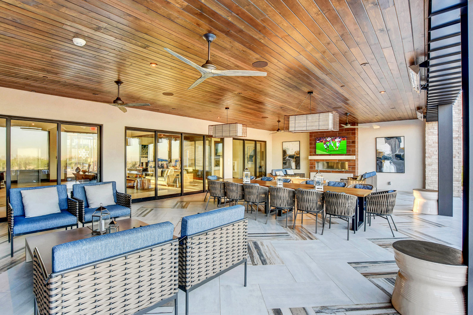 Covered outdoor dining and lounge area at the Outlook Club with a fireplace and television