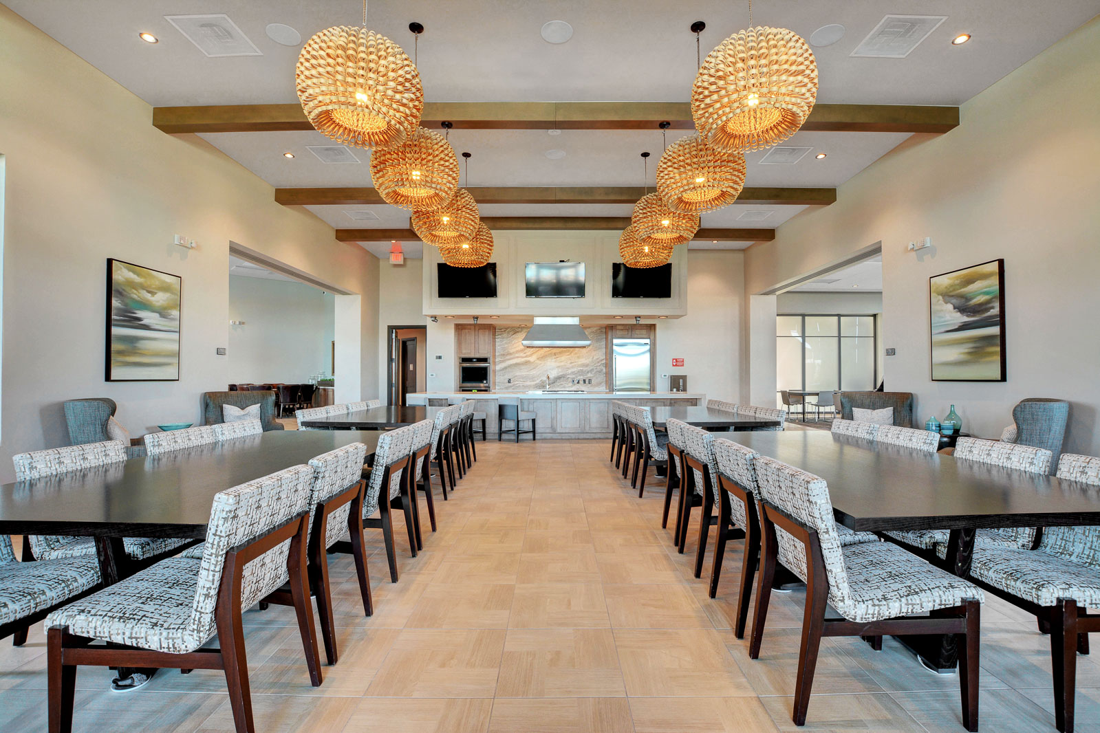 Community dining hall with long tables and a demonstration kitchen at the Regency clubhouse