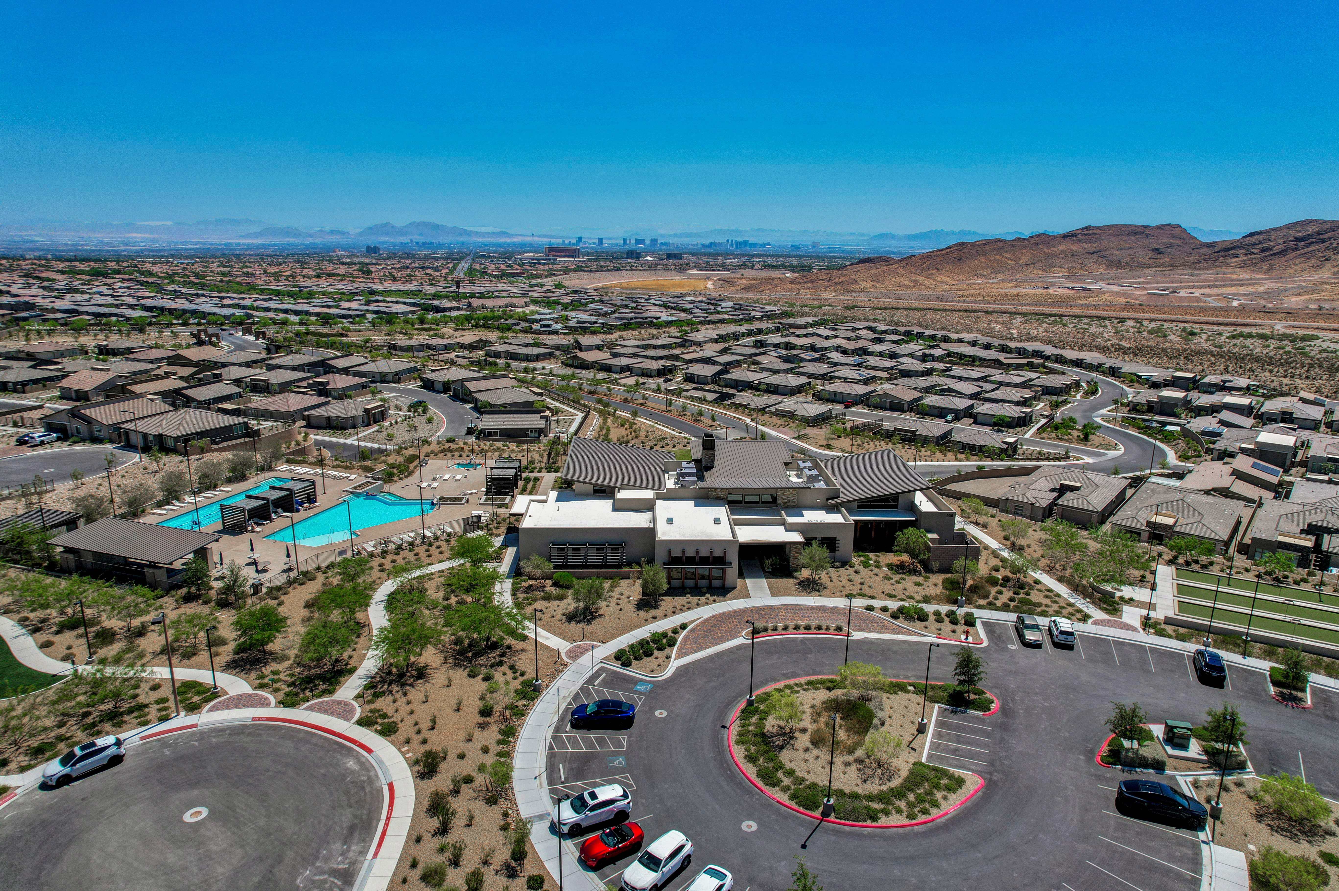 Aerial view of the Heritage at Stonebridge clubhouse, pool, and parking area with the Las Vegas Strip skyline in the distance