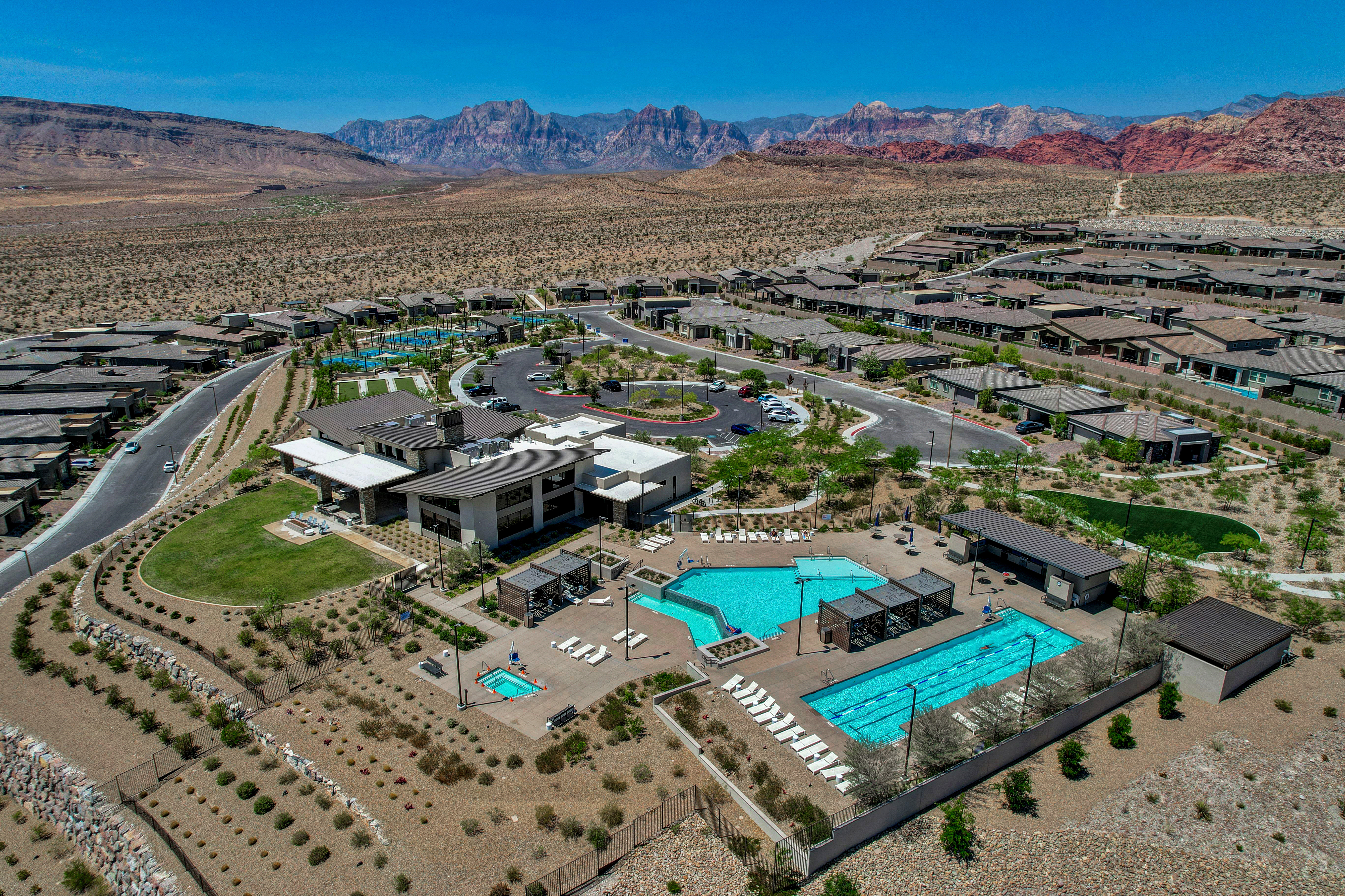 Aerial view of the Heritage at Stonebridge clubhouse, pools, and parking area with Red Rock Canyon in the background