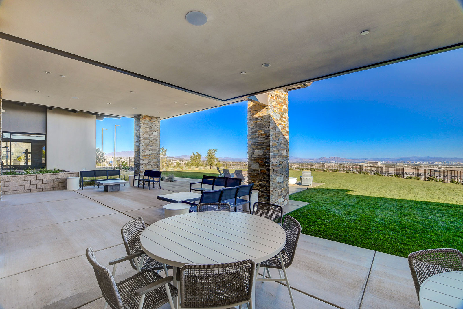 Covered patio with dining tables and lounge seating overlooking the lawn and valley at the Heritage at Stonebridge clubhouse