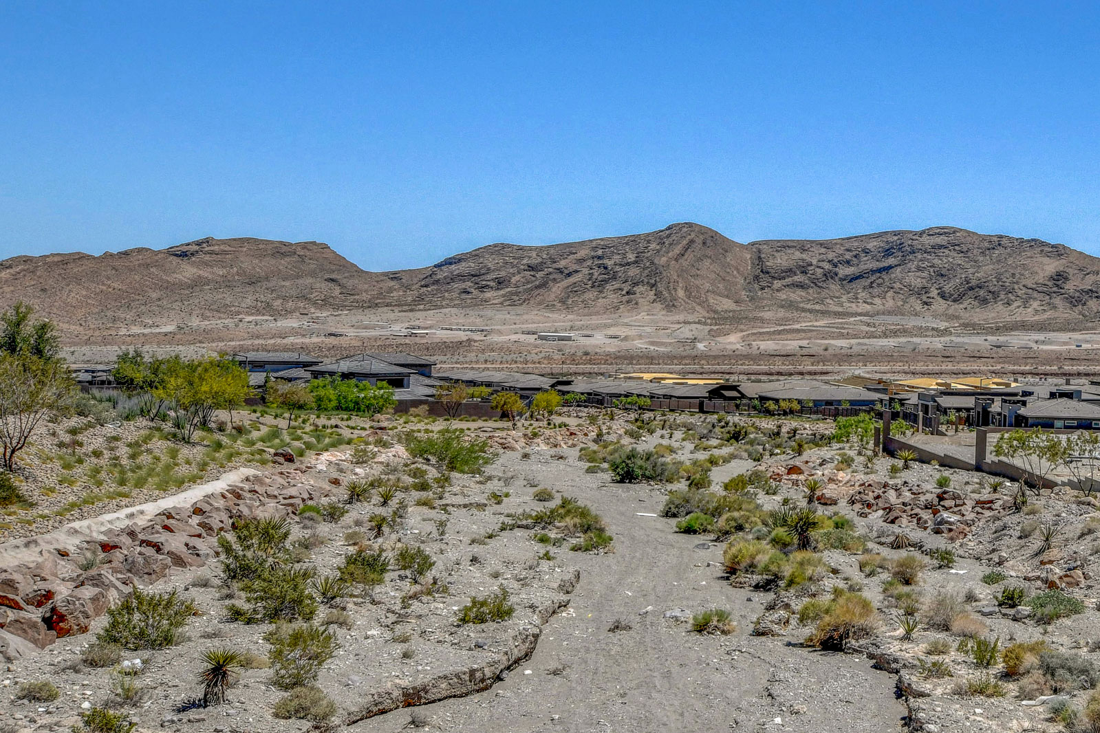 Desert wash trail near Heritage at Stonebridge with mountain views and the community visible in the distance