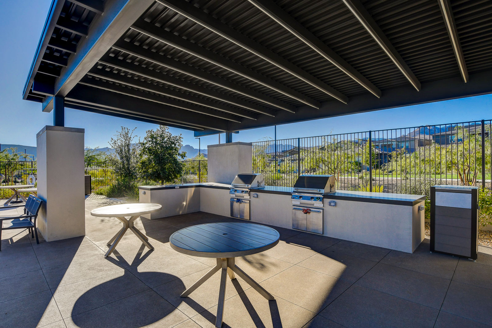 Covered outdoor kitchen with built-in grills and dining tables at the Heritage at Stonebridge clubhouse