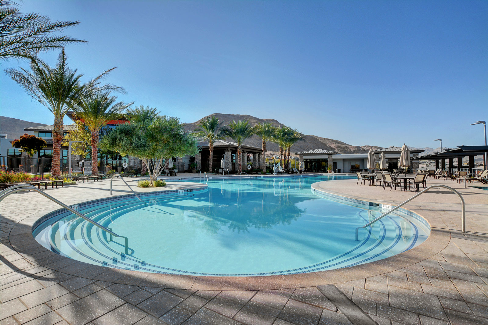 Outdoor resort-style pool and spa with palm trees, shaded cabanas, and mountain views at the Regency clubhouse