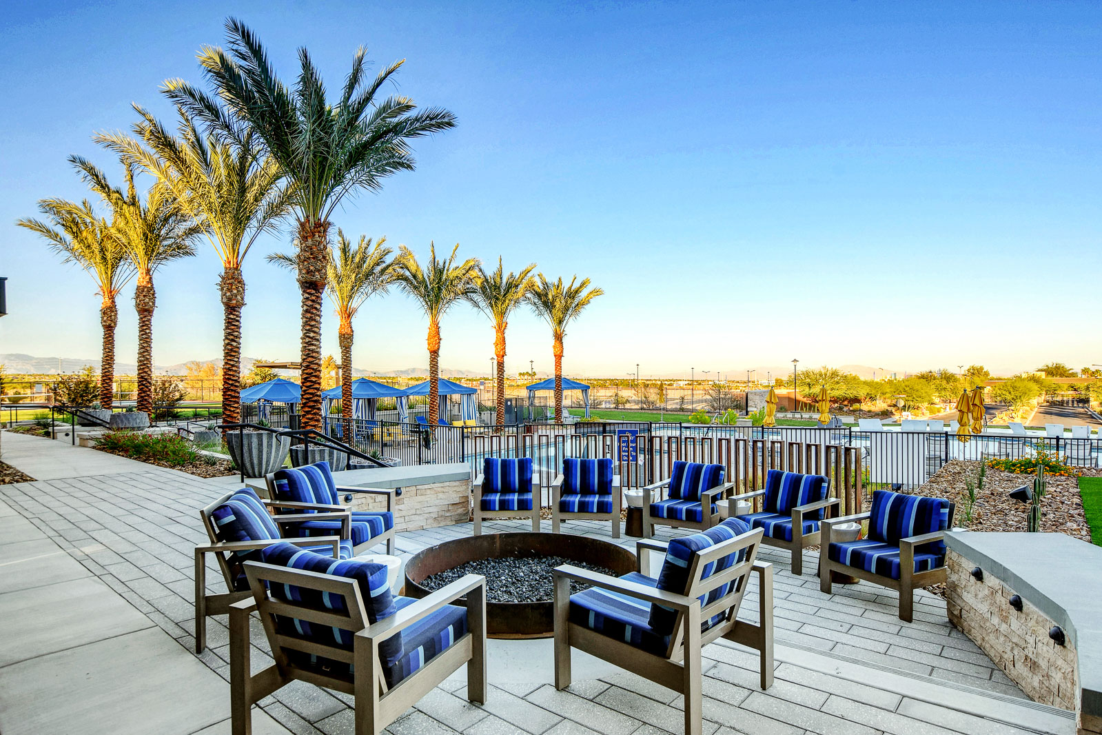 Fire pit lounge seating near the pool at the Outlook Club with palm trees at twilight