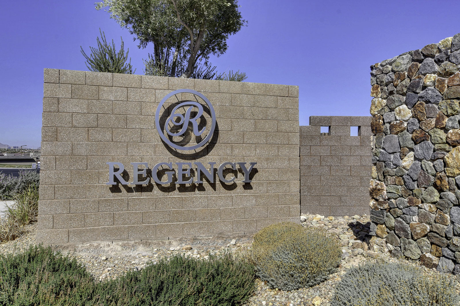 Regency monument sign with stone wall and desert landscaping at the community entrance in Las Vegas, Nevada