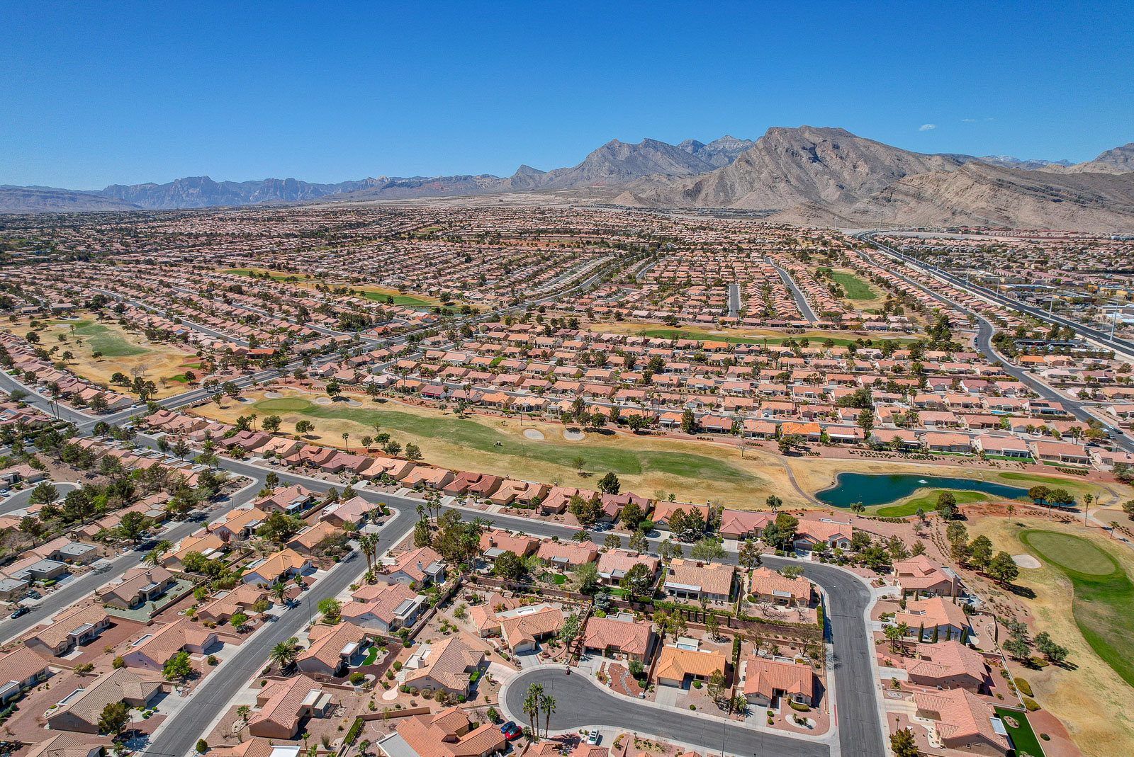 Aerial view of Sun City Summerlin neighborhood homes bordering a golf course pond in Las Vegas, Nevada